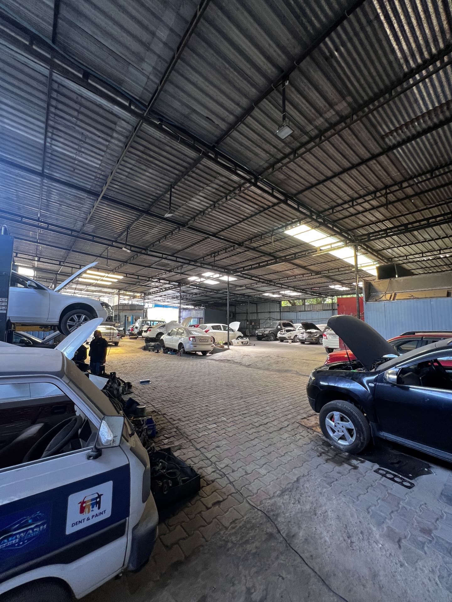 Wide interior view of the Pune Automotive workshop with several cars under service